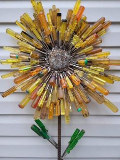 a sunburst made out of glass bottles on a white wall next to a tree