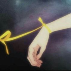 two hands holding on to a string with a yellow ribbon tied around the end of it