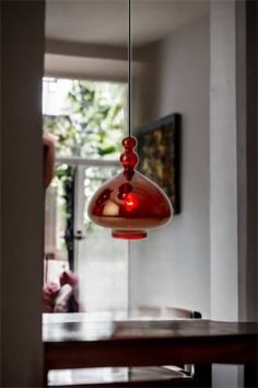 a red light hanging from the ceiling in a room with a wooden table and chairs