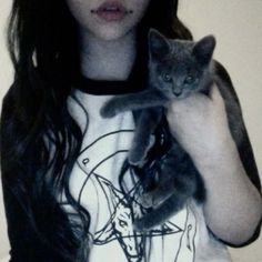 a woman is holding a cat in her arms while wearing a t - shirt with the image of jesus on it