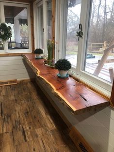 two potted plants are sitting on a long wooden table in front of a window