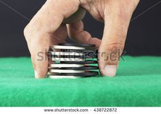 a man stacking poker chips on top of a green table with black and white background