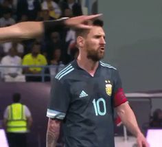 two men are playing soccer in front of an audience and one is holding his head