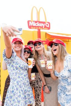 four women pose for a photo in front of a mcdonald's sign with their cups