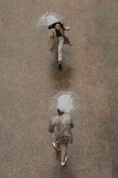 two people walking in the rain with umbrellas