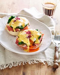 two sandwiches with ham, cheese and vegetables on a plate next to a glass of coffee