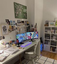 two computer monitors sitting on top of a desk in front of a book shelf filled with books