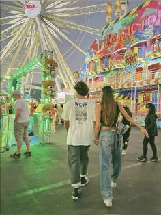 two people walking in front of a carnival ride