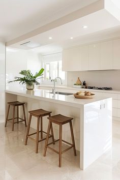 a kitchen with two stools and an island in the middle of the room that has plants on it