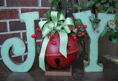 the word joy is made out of wood and decorated with green ribbon, berries and bow