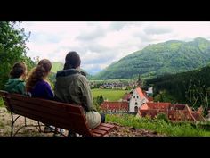 three people are sitting on a bench looking at the countryside