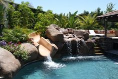 a backyard with a pool and waterfall in the middle