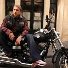 a man sitting on the back of a motorcycle in front of a building with windows