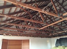 an unfinished room with exposed wood beams and blinds on the ceiling, along with other pieces of furniture