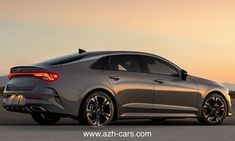 the rear end of a silver car parked in an empty parking lot at sunset with mountains in the background