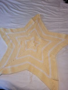 a yellow crocheted star laying on top of a bed