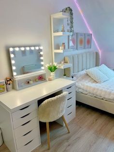 a bedroom with a bed, desk and mirror in the corner is lit up by bright lights