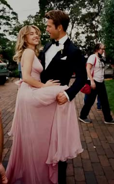 a man in a tuxedo standing next to a woman in a pink dress