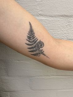 a black and white photo of a fern tattoo on the arm