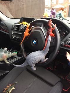 two toy dinosaurs on the steering wheel of a car