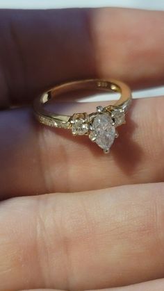 a woman's hand holding a yellow gold ring with two diamonds on it,