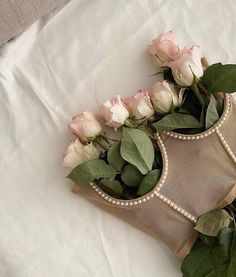 some pink roses and green leaves on a white sheet