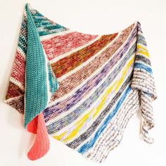 a multicolored shawl hanging on a white wall next to a pair of scissors