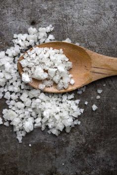 a wooden spoon filled with white sugar on top of a table next to a pile of chopped