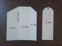 two white tags with measurements on them sitting on a table