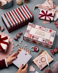 a person holding a notepad next to some gift boxes and other items on a table