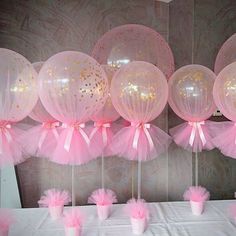 pink and gold balloons are on display in front of white table cloths with tulle