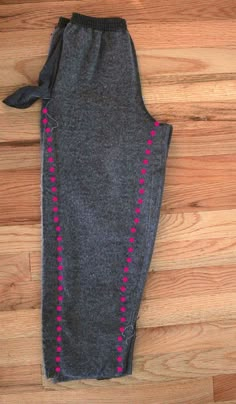 a pair of leggings with pink and black beads on them sitting on a wooden floor