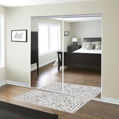 an empty bedroom with a large mirror on the wall and a bed in the background