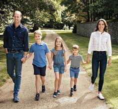 a family walking down a dirt road in the middle of a park, holding hands and smiling