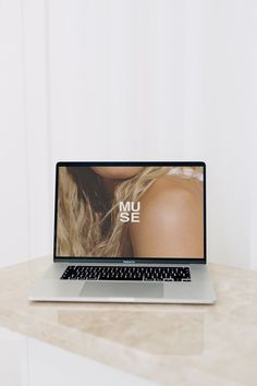 an open laptop computer sitting on top of a wooden table next to a white wall