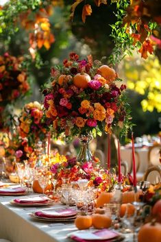 the table is set with oranges and flowers in vases, candles, and plates