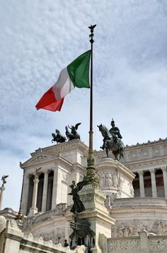 the italian flag is flying in front of an ornate building with statues on it's sides