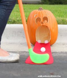 a person standing next to a fake pumpkin