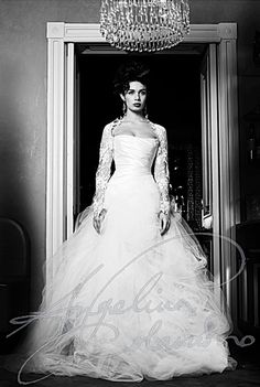 a black and white photo of a woman in a wedding dress standing in an open doorway