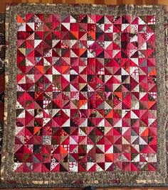 a red and black quilt on top of a wooden floor