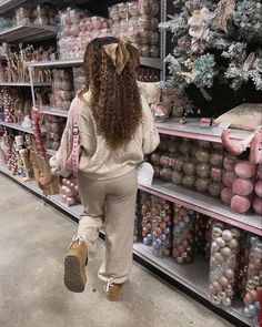 a woman walking through a store filled with christmas ornaments