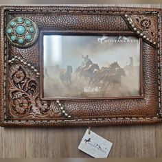 an old photo frame with horses running in the desert on it's side and a tag hanging from the front