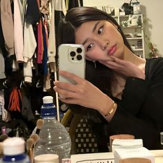 a woman taking a selfie with her cell phone in front of the camera while sitting at a dressing room table