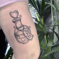 a small tattoo on the leg of a woman with a bottle and heart in it