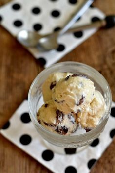 two scoops of ice cream sit in a glass bowl on a polka dot napkin