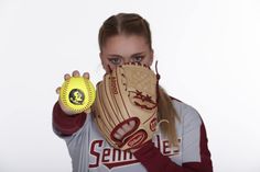 a woman wearing a catchers mitt holding a softball