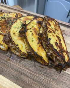 four pieces of grilled food sitting on top of a wooden cutting board