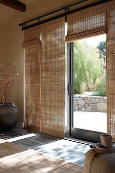 a large vase sitting on top of a wooden floor next to a window covered in bamboo blinds