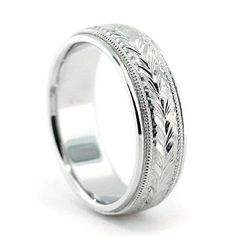 a wedding ring with engraved leaves on the side and engraving inlays to it