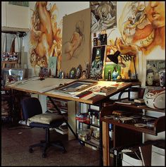 an art studio with many paintings on the wall and desks in front of it